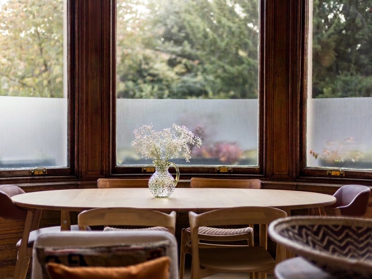 Dining table in a wood-framed bay window, interior design project by Seonaid Johnston